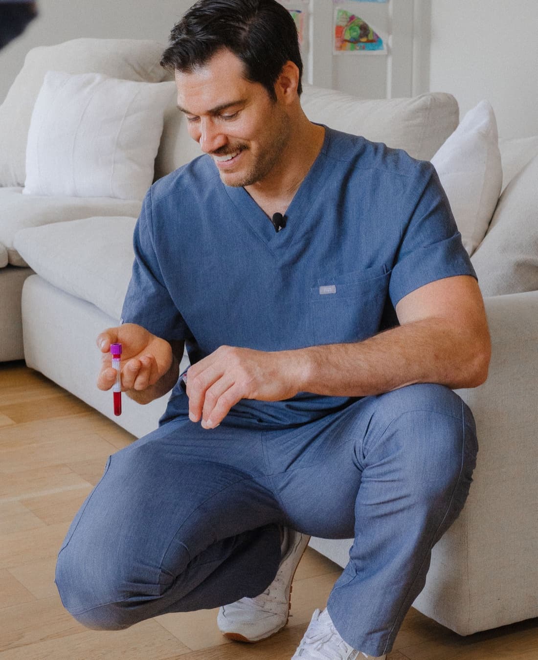 Dr. Evan Antin, Chief Medical Officer, in scrubs holding a blood-sample vial.